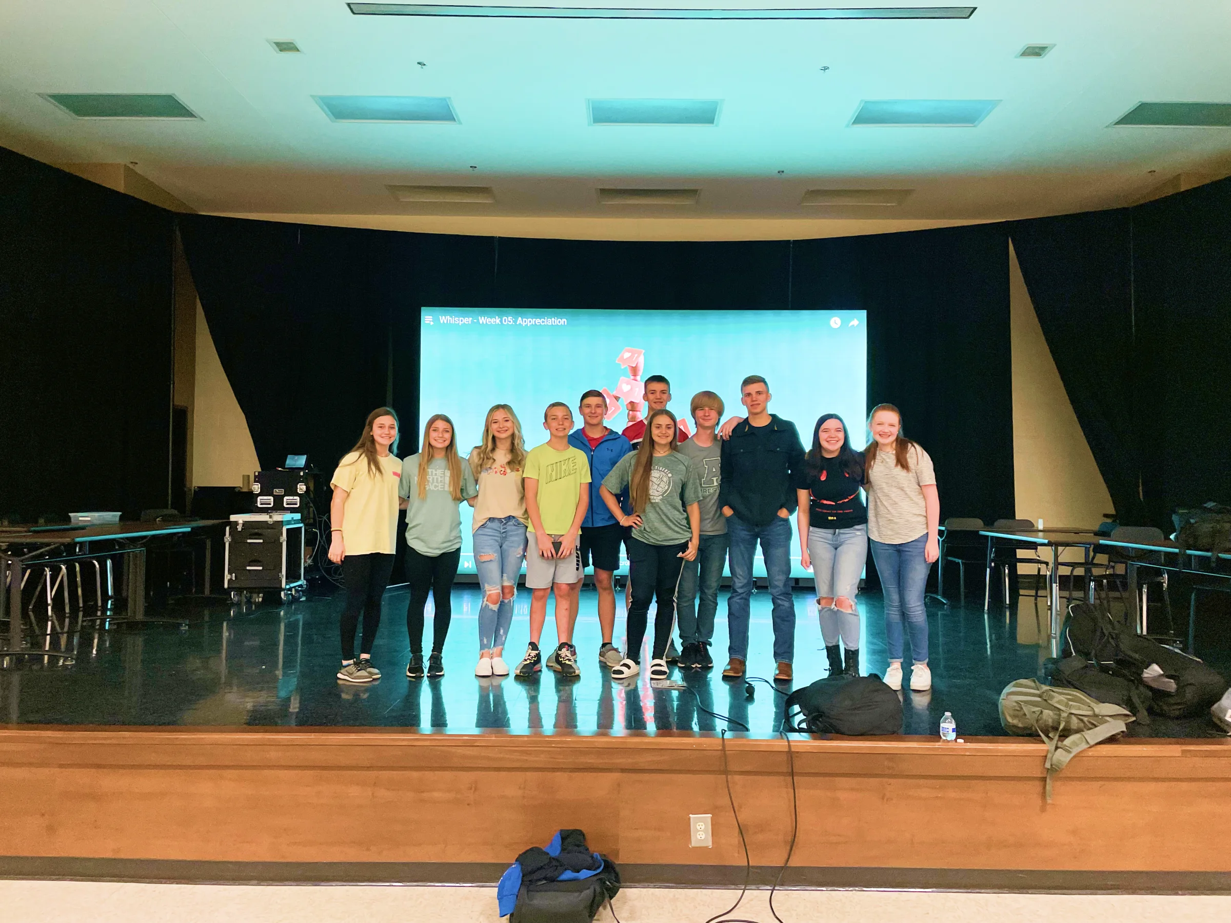 Student leaders lined up on stage in front of a Whisper slide