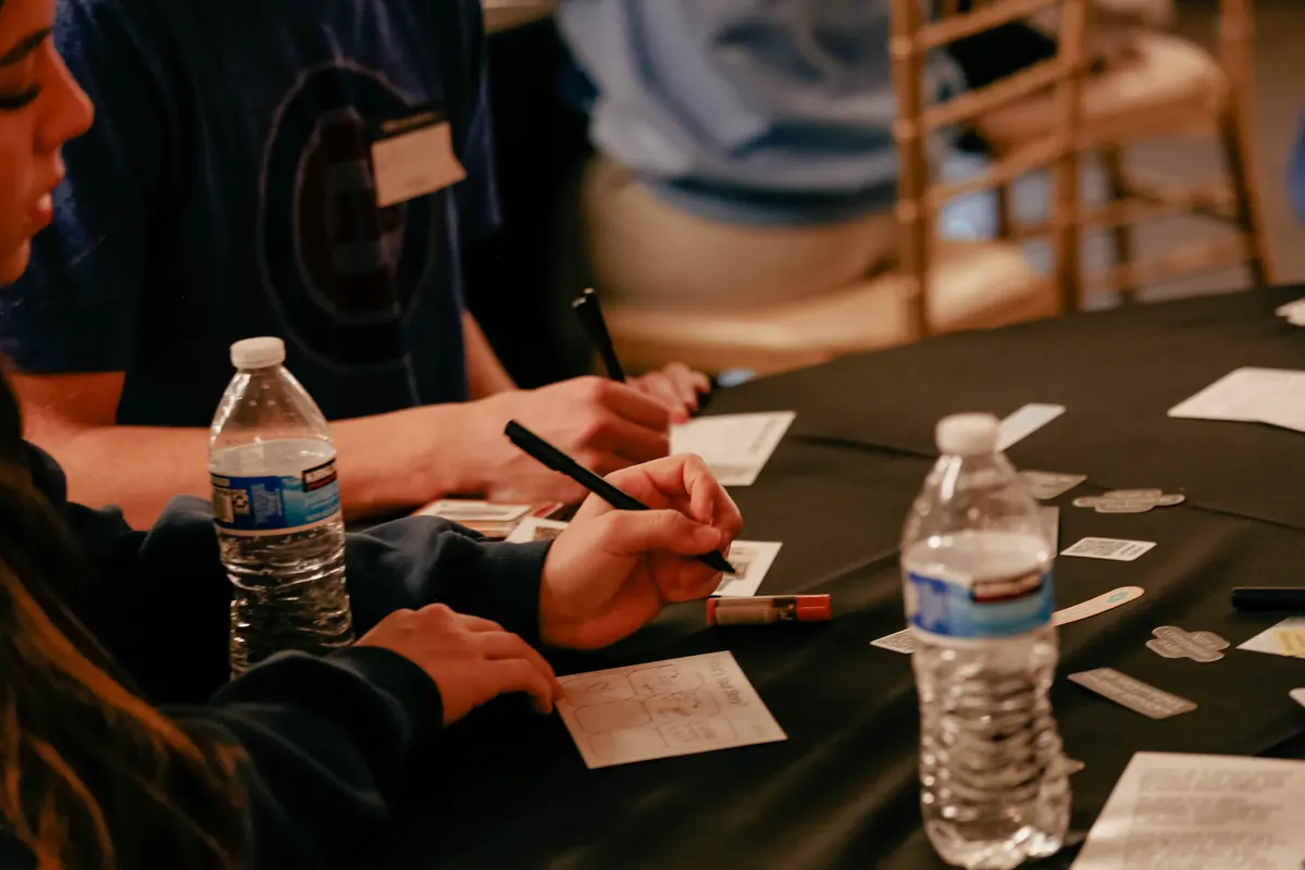 Students writing on cards at a gathering table