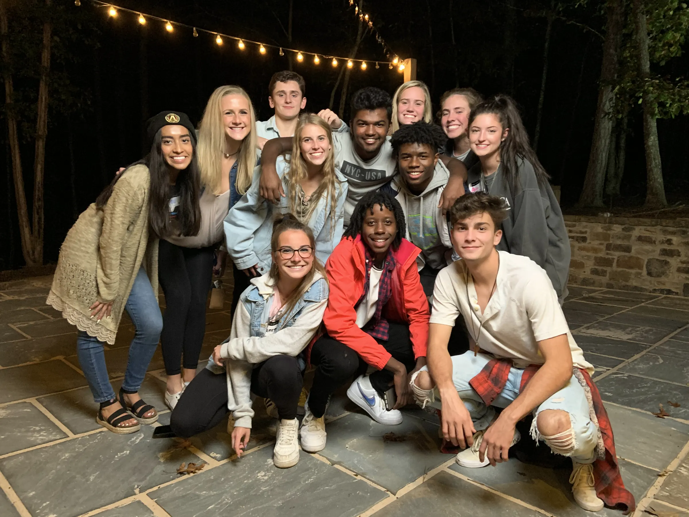A group of students posing together under string lights after a Whisper gathering